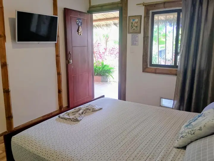 Habitación con cama doble y puerta abierta hacia el jardín