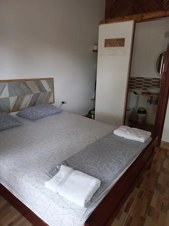 Habitación con cama amplia, toallas dobladas y vista hacia el baño