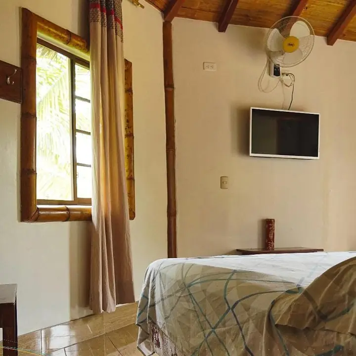Habitación con cama, televisor en la pared y ventana de madera
