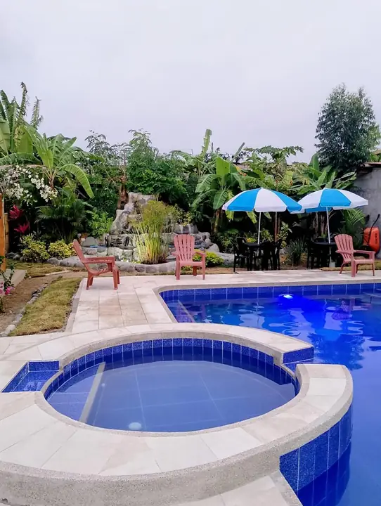 Piscina con una piscina pequeña redonda elevada, sombrillas y tumbonas